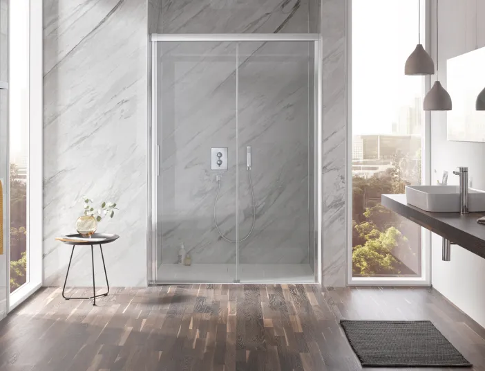 Luxuriöses Badezimmer mit Glasdusche HSK Atelier Plan, Marmorverkleidung und dunklem Holzboden. Großzügiges Fenster sorgt für Licht.